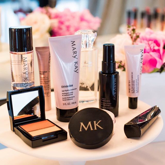 Mary Kay cosmetics are displayed against a pink, floral backdrop.