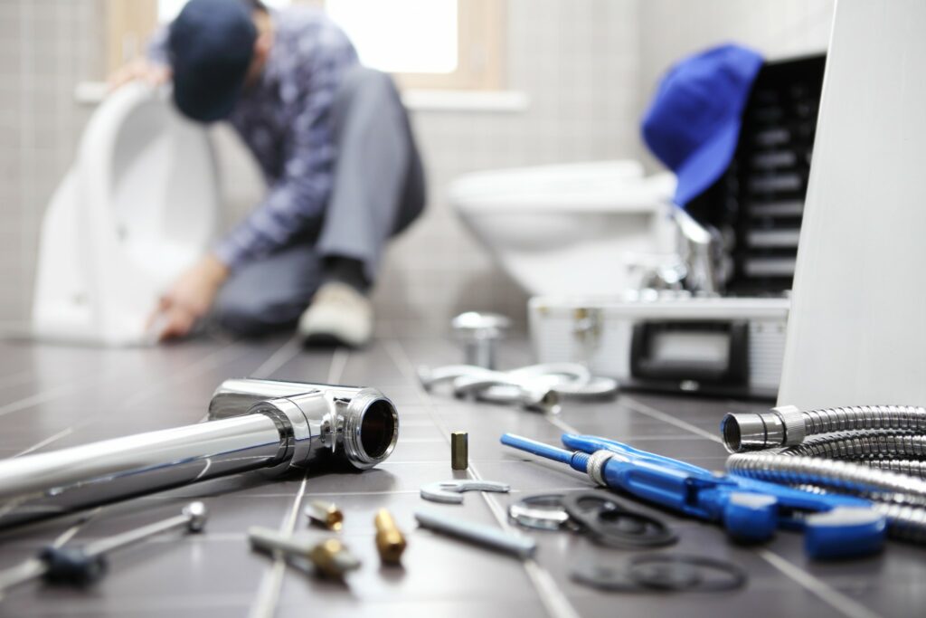 A plumber works in a bathroom with tools and piping. 